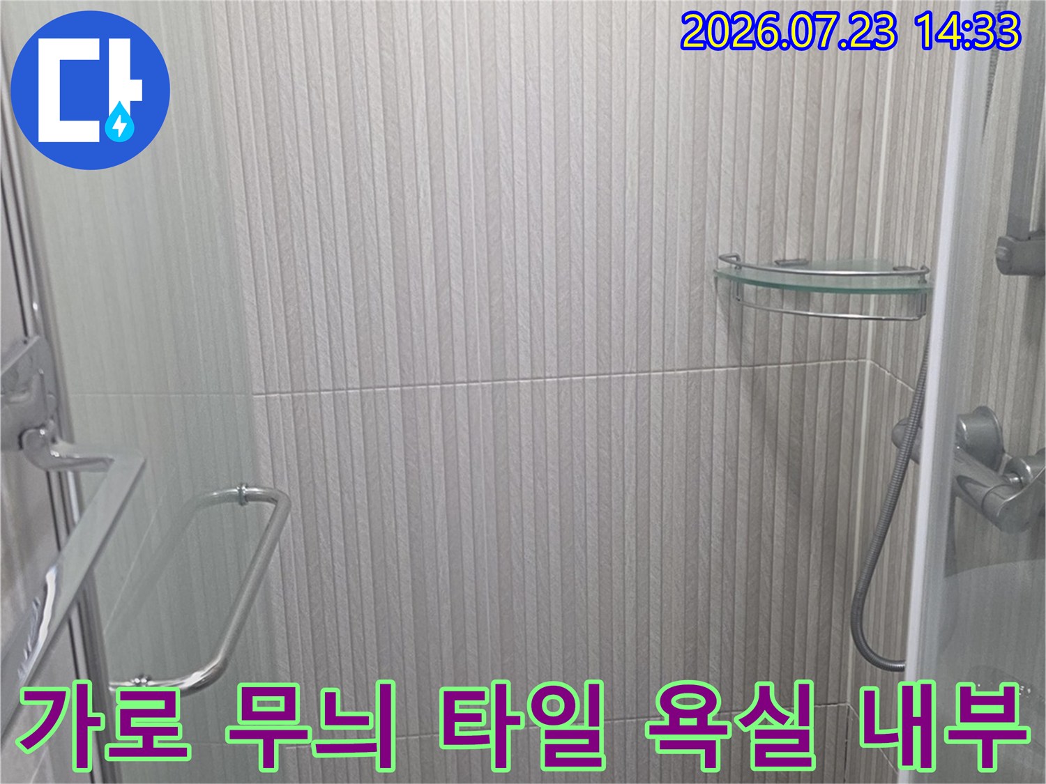 가로 줄무늬 패턴의 벽 타일과 은색 안전 손잡이가 설치된 샤워 공간