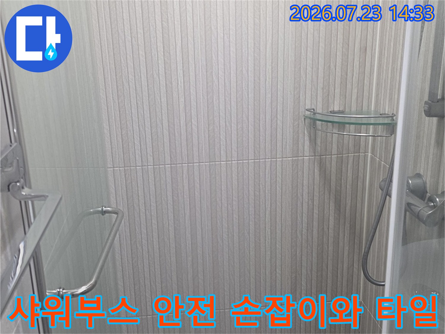 샤워부스 내부에 설치된 스테인리스 손잡이와 그 주변의 밝은 회색 타일 벽면