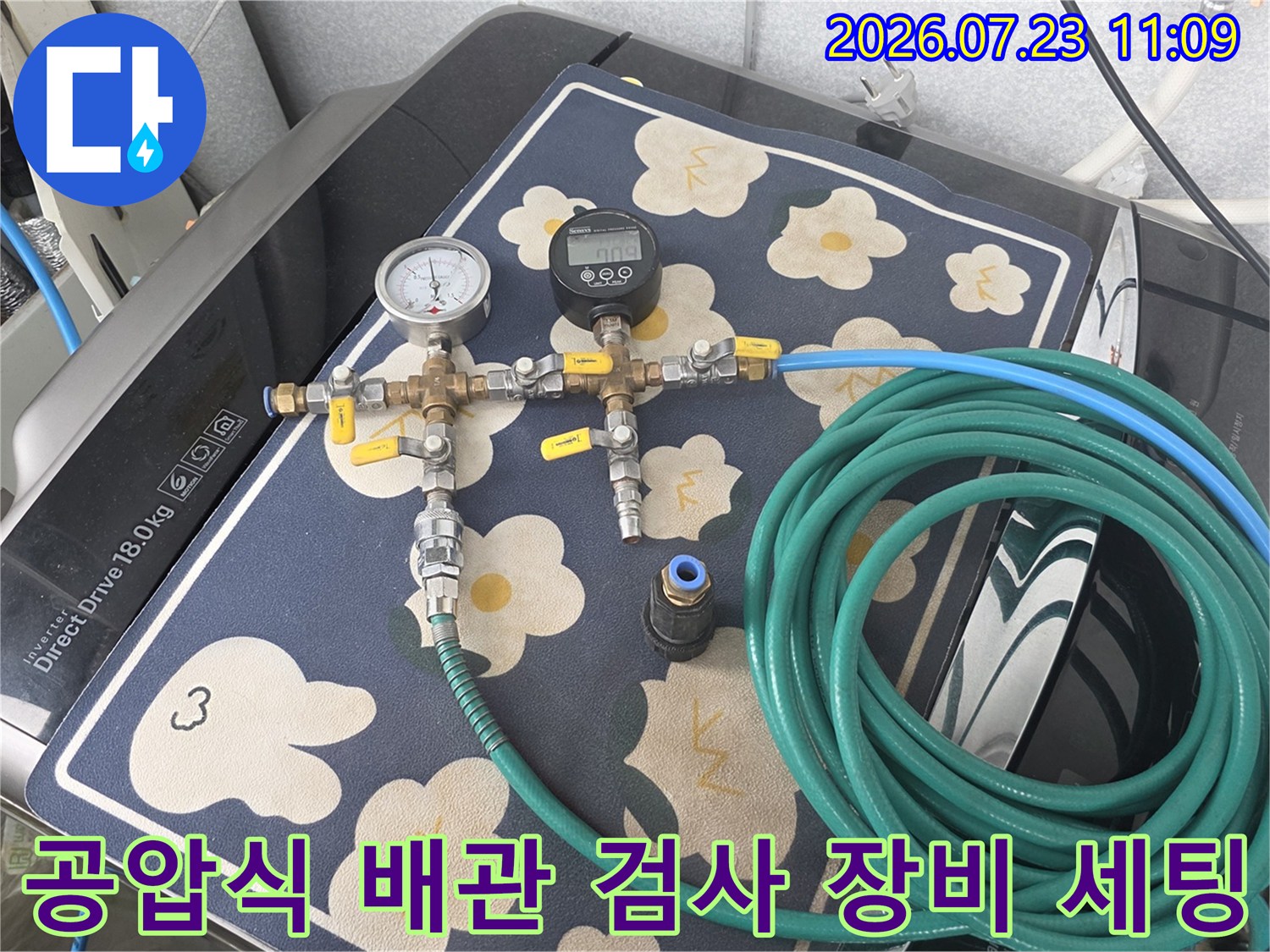 금속제 밸브와 압력계가 결합된 누수 탐지 도구-초록색 호스가 길게 말려 있는 모습