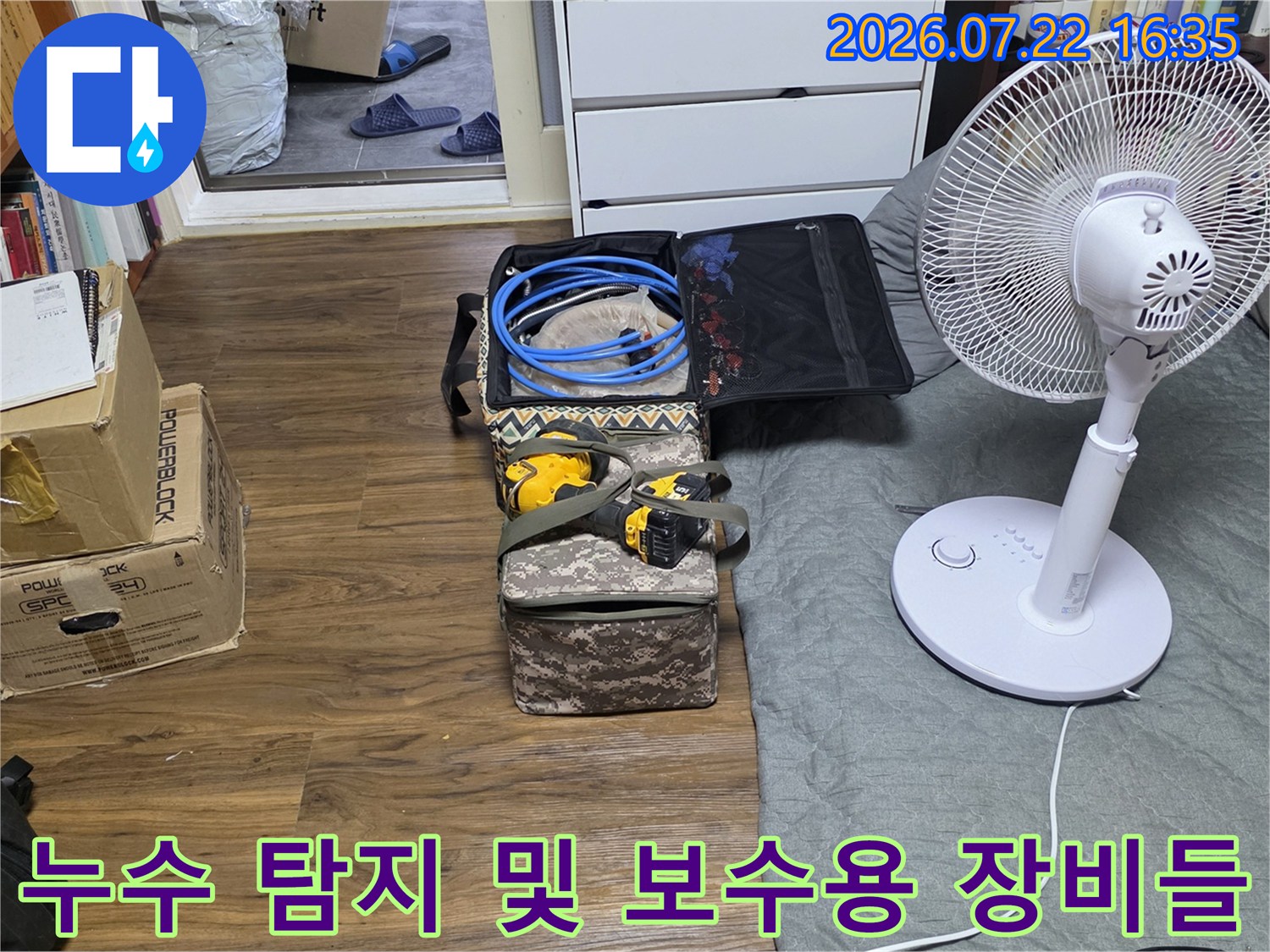 열려 있는 공구함 속에 들어있는 파란색 배관 호스와 노란색 전동 드릴-거실 바닥 배치
