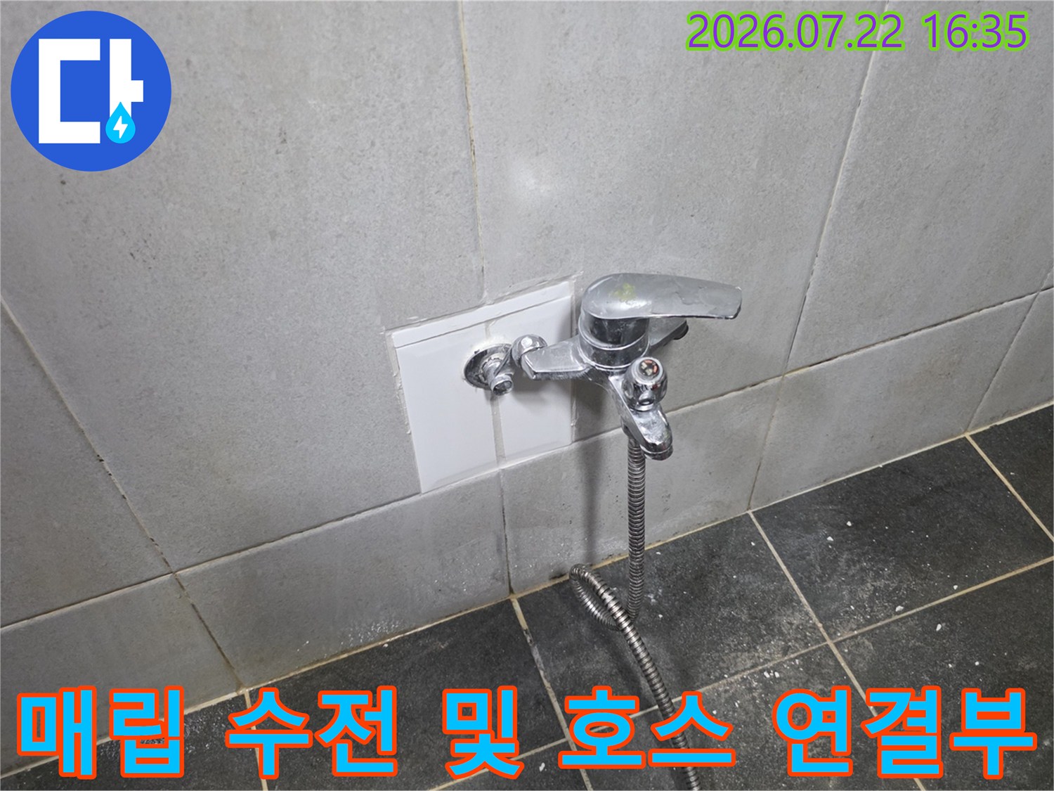 타일 벽면에 고정된 수도꼭지와 아래로 늘어진 은색 샤워 호스 형태의 배관