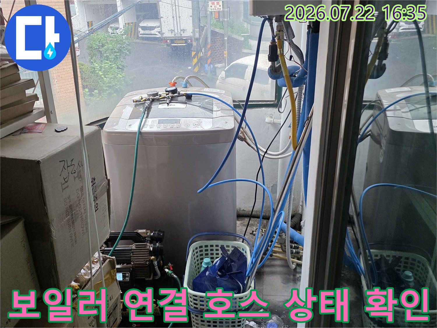 흰색 보일러 장비 아래로 늘어진 파란색 배관과 주변 정리함이 놓인 현장 사진