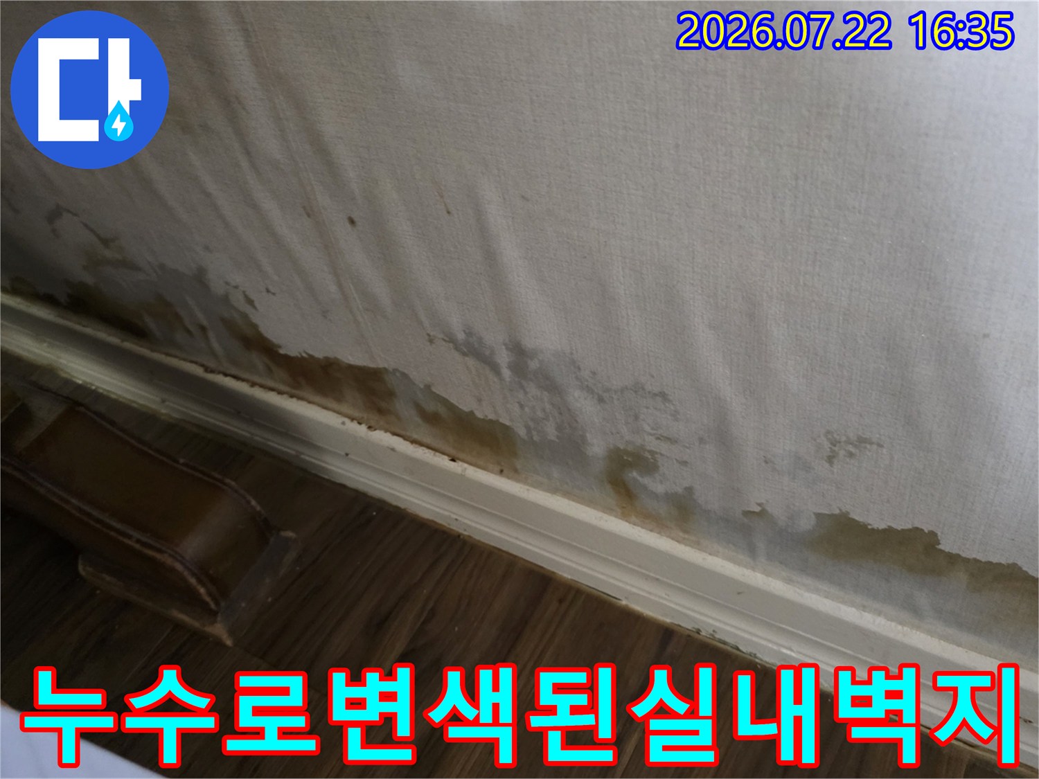 흰색 실내 벽지의 아래쪽 부분이 물에 젖어 갈색으로 변색되고 얼룩진 모습