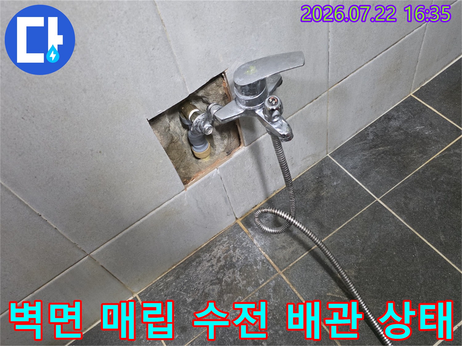 흰색 타일 벽면에 설치된 은색 수도꼭지와 연결된 금속 호스-매립 배관 부위 노출