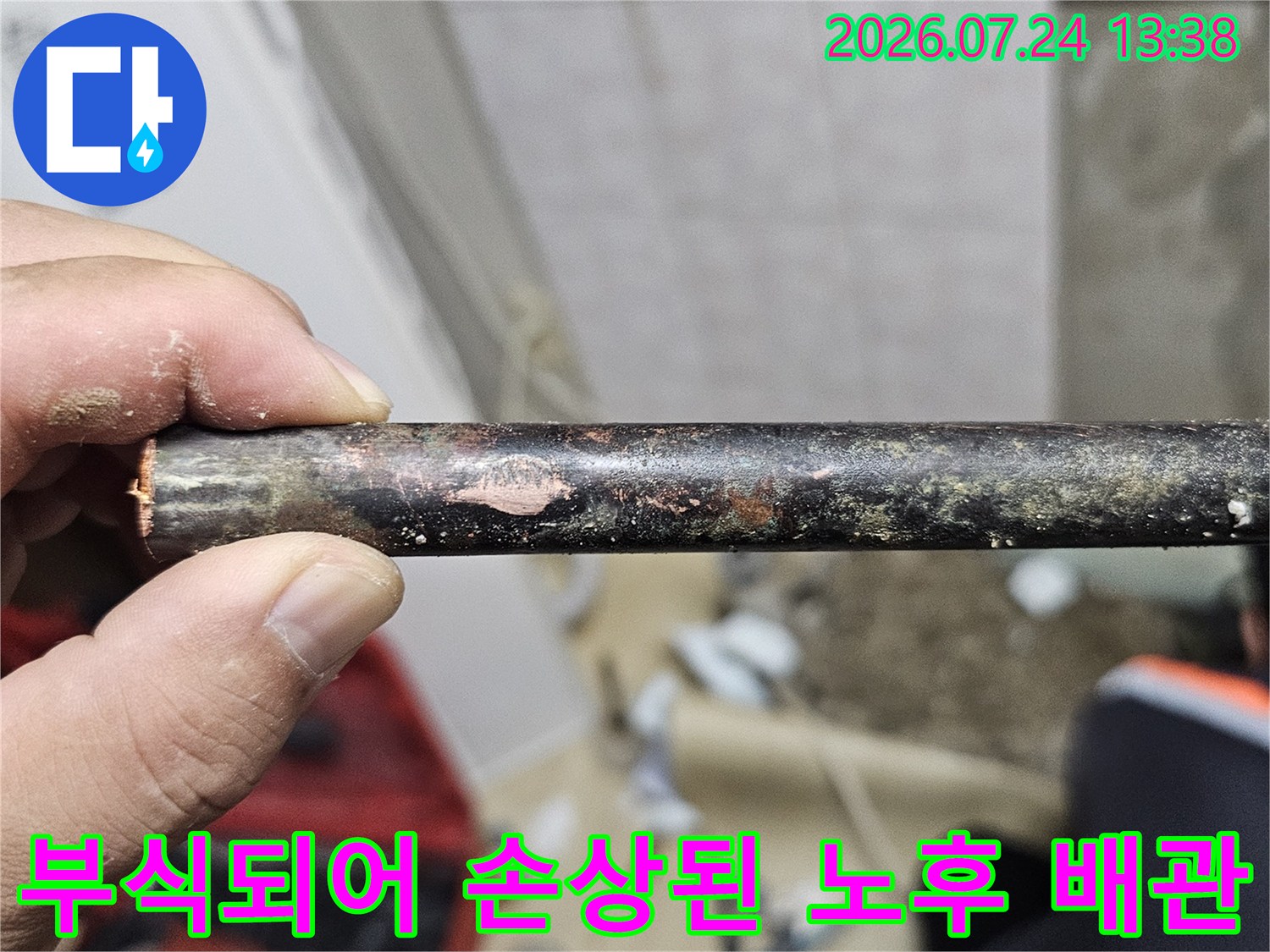 손으로 잡고 있는 심하게 부식되어 표면이 거칠어진 검은색 금속 배관-사진