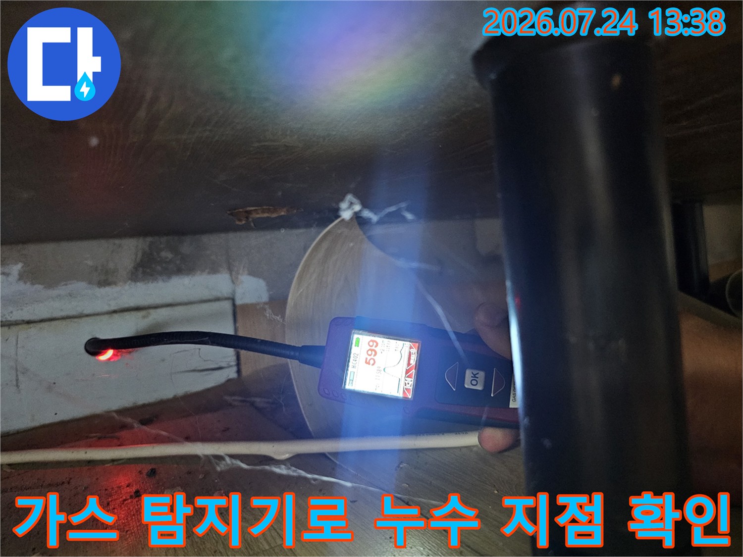 좁은 공간에서 디지털 가스 탐지기를 사용하여 배관의 누수 지점을 추적하는 모습
