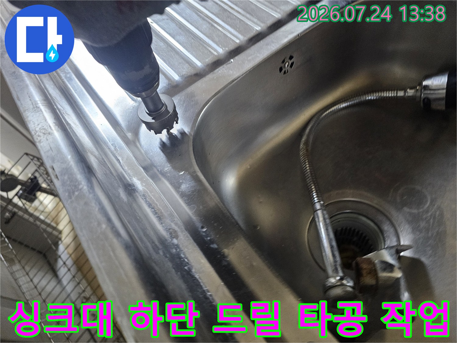 주방 싱크대 스테인리스 상판 부근에서 드릴 장비를 이용해 타공 작업을 진행하는 모습