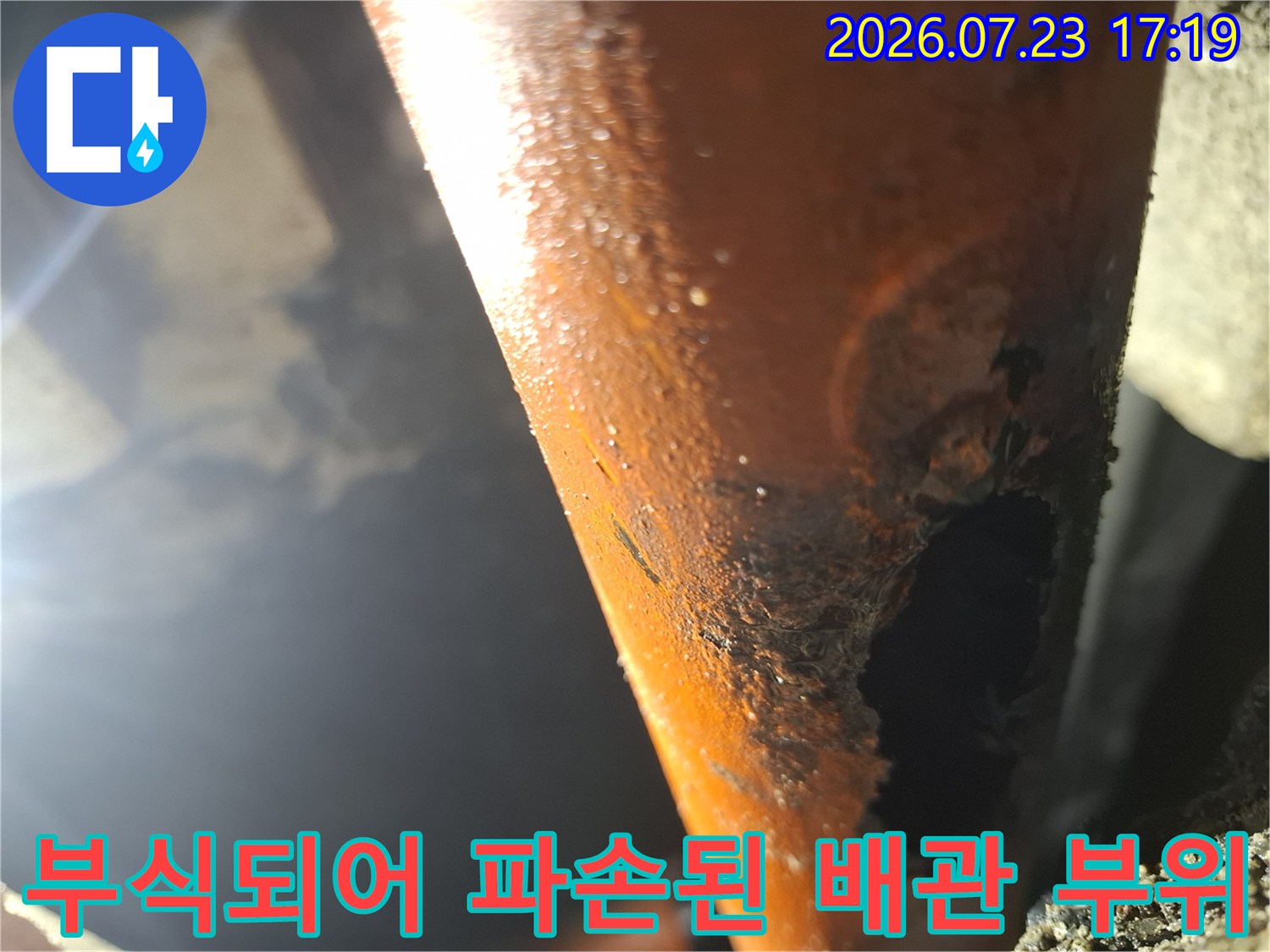 오렌지색 배관의 외벽이 산화되어 껍질처럼 일어나고 구멍이 크게 뚫린 모습