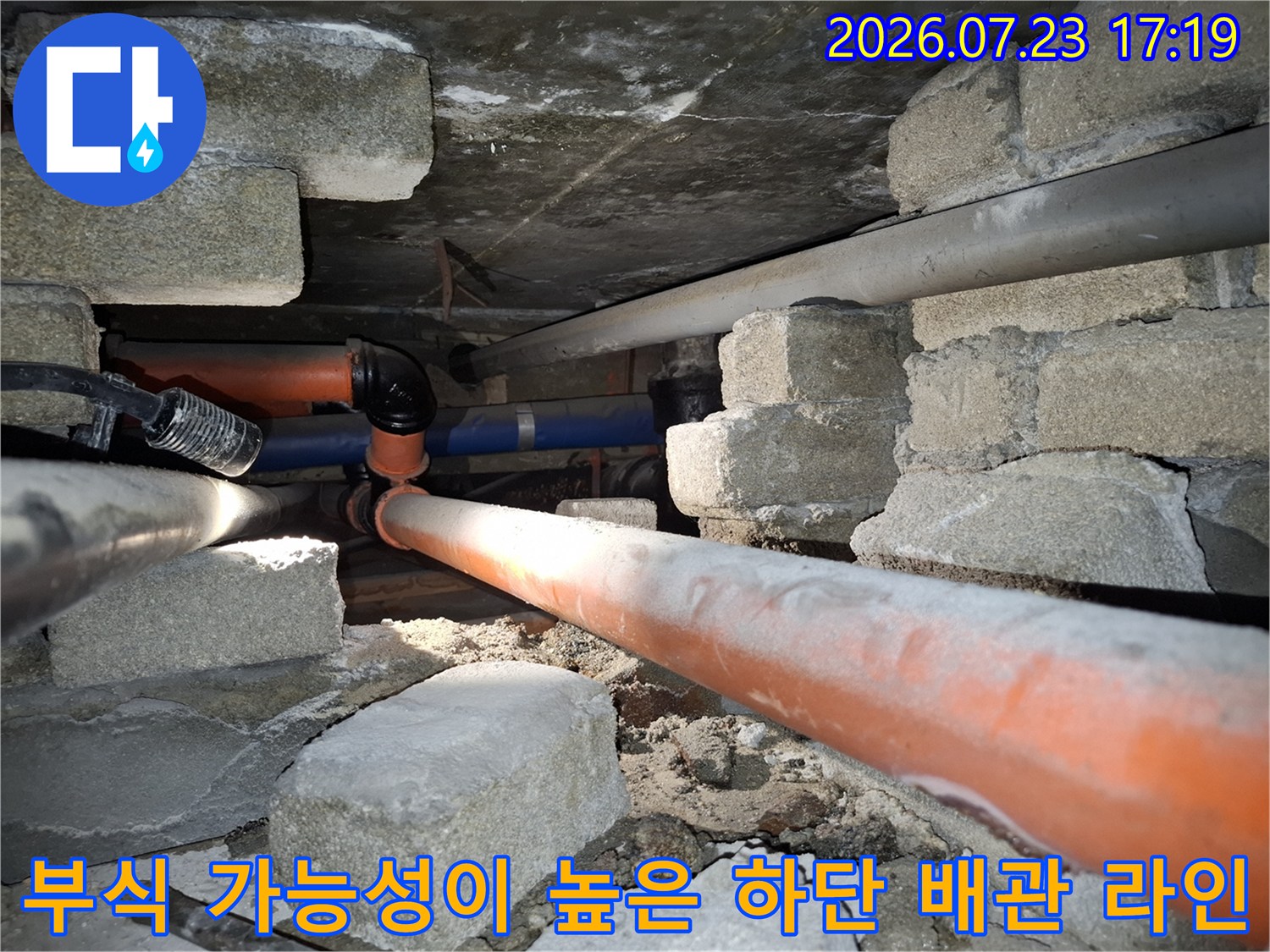 콘크리트-블록-사이로-설치된-오렌지색-배관과-파란색-배관의-교차-지점