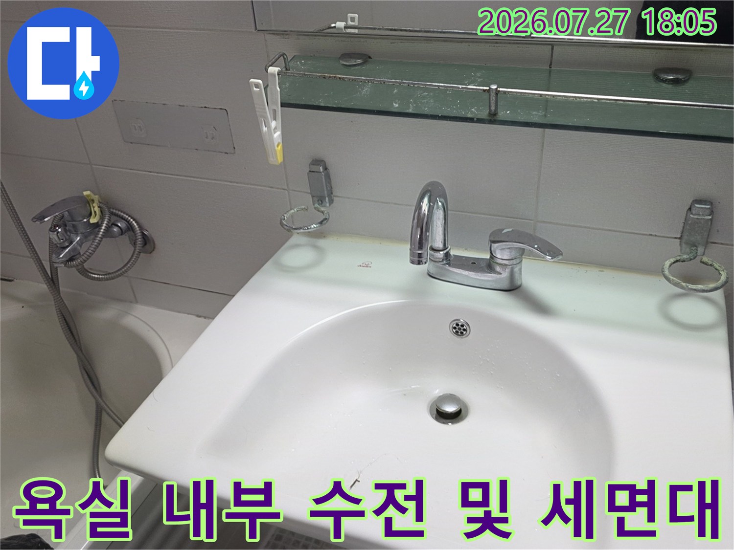크롬 도금된 세면대 수전-그리고 뒤편의 유리 선반과 하얀색 타일 벽면 모습