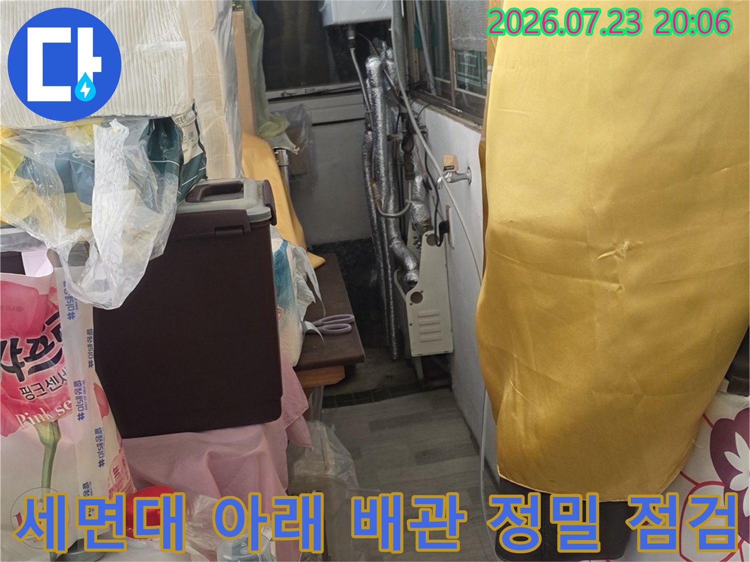 화장실 세면대 하부의 얽힌 배관들을 면밀히 조사하며 누수 여부를 판단하는 사진
