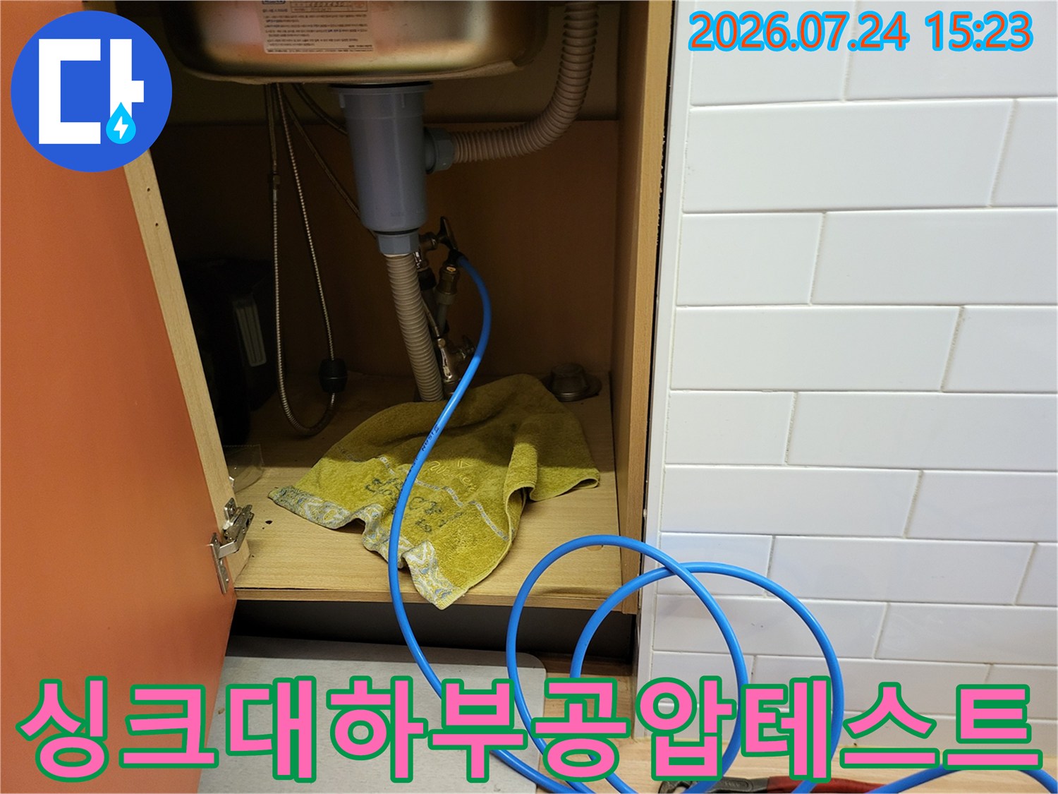싱크대-하부장-내부에-파란색-공압-호스를-연결하여-배관-기밀-테스트를-진행하는-모습