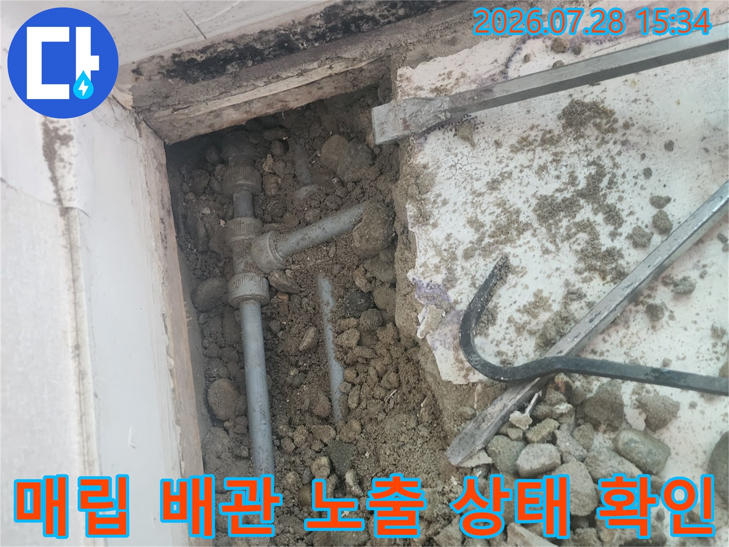 흙과 자갈 사이로 드러난 수도 배관 연결부의 상세 모습