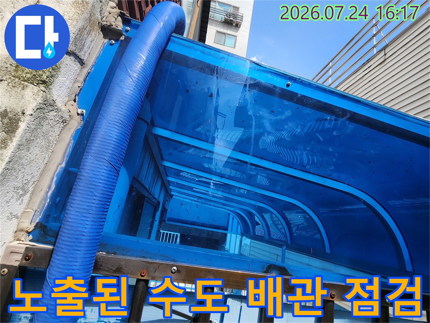 벽돌 벽면에 고정되어 파란색 보온재로 감싸진 노출 배관 사진