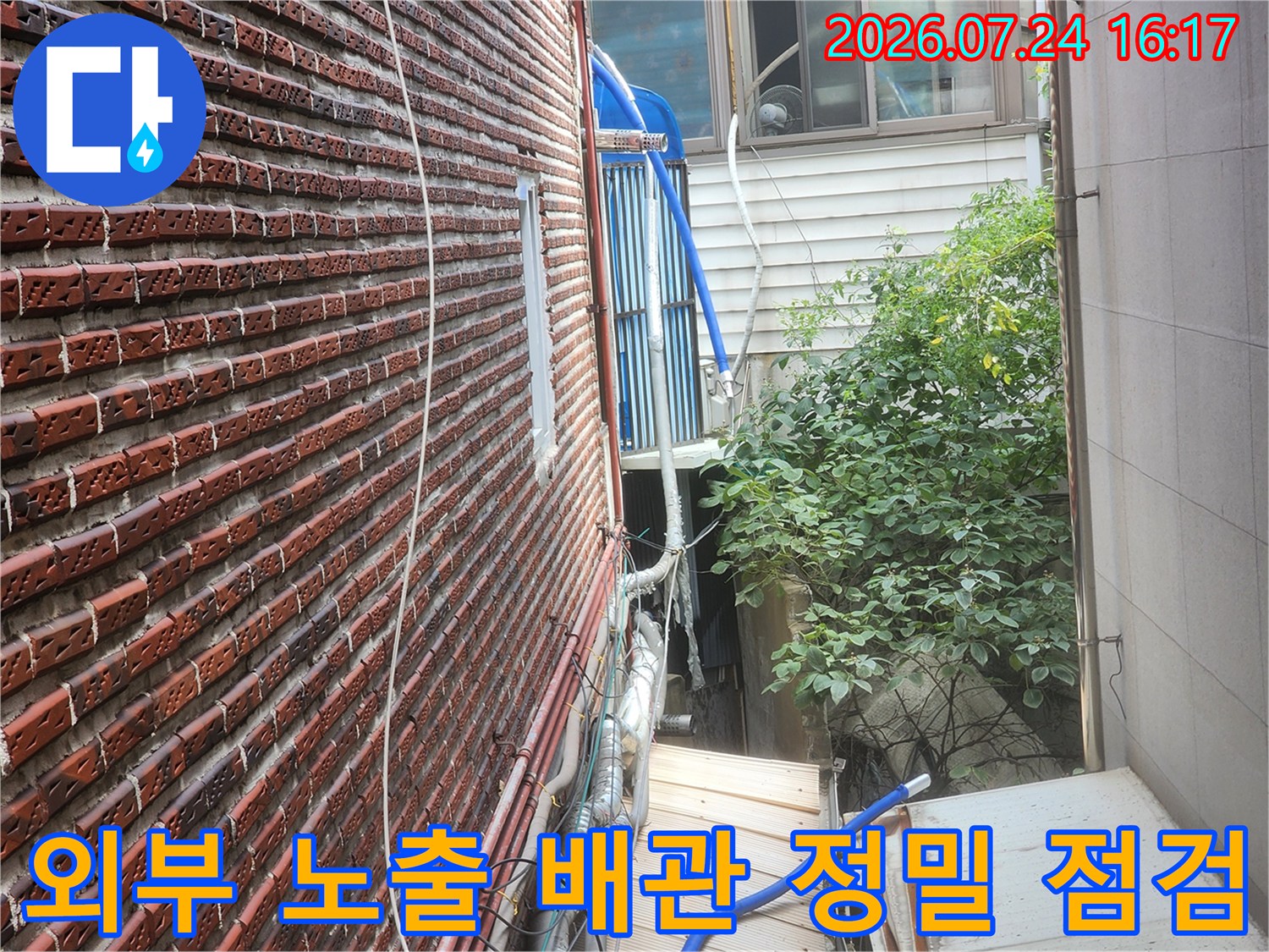 벽돌 외벽에 설치된 파란색 보온재와 은색 단열재가 덮인 수도 배관라인
