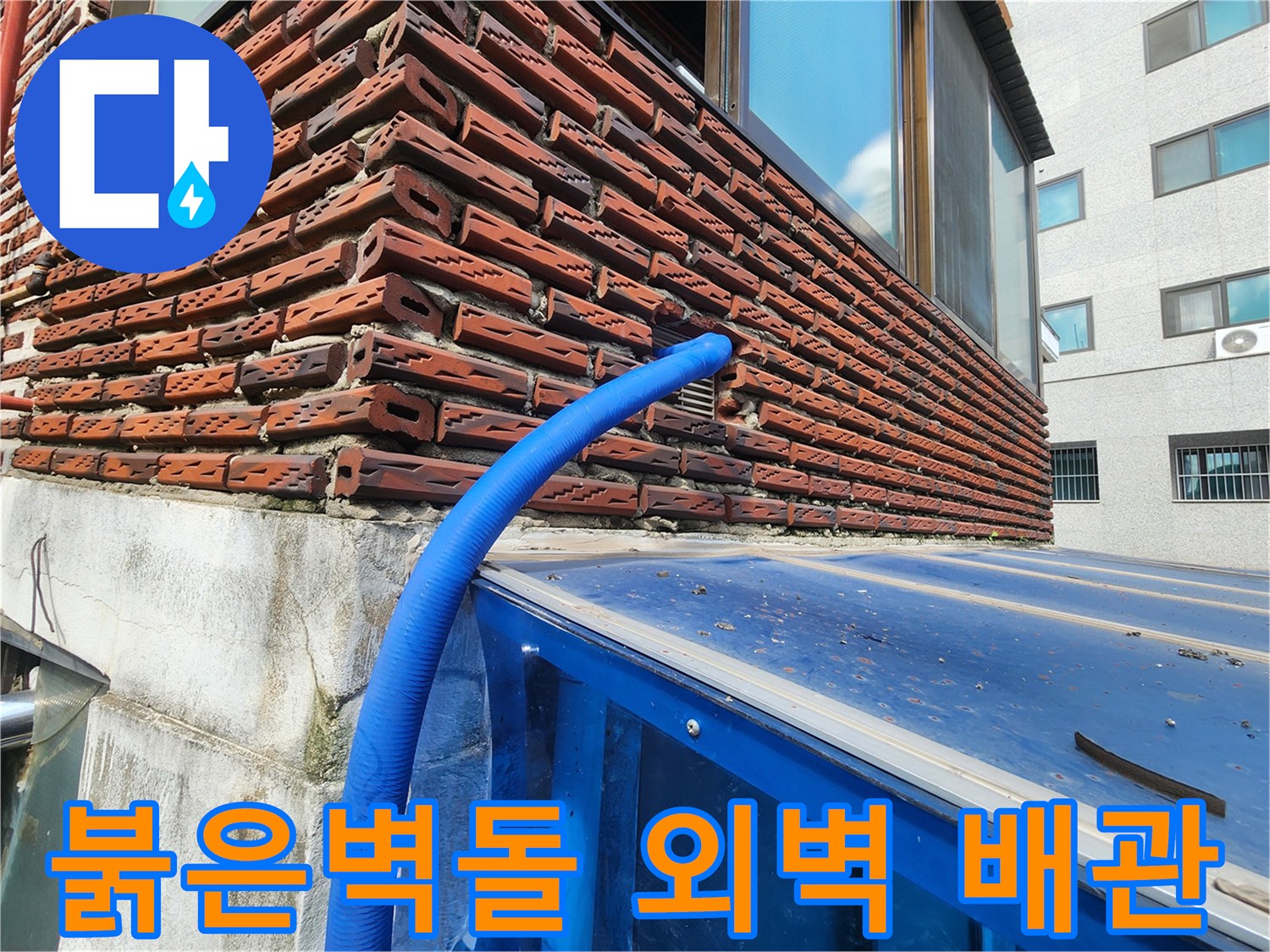 붉은색 벽돌 외벽에 설치된 파란색 보온재 배관 모습