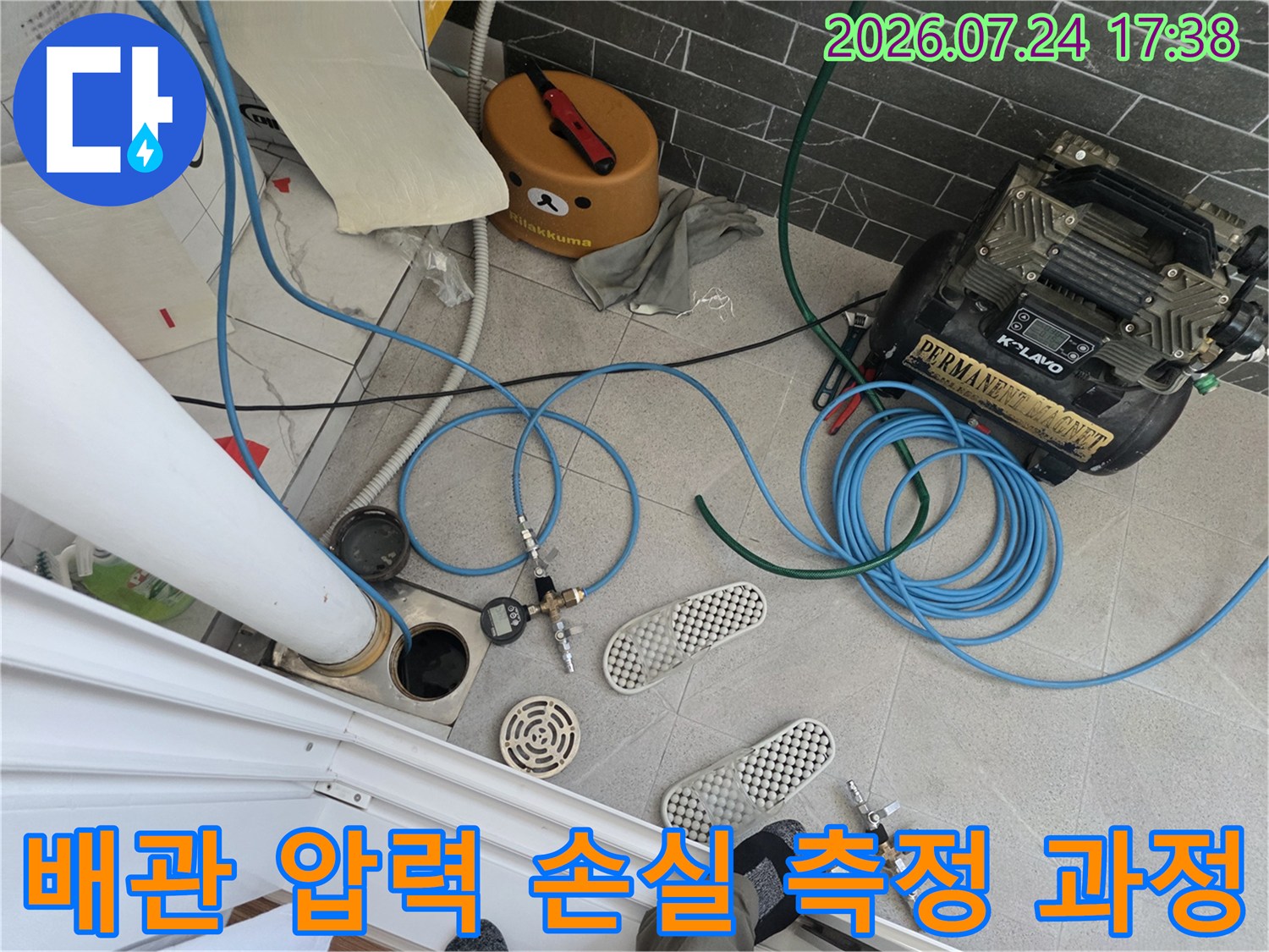 콤프레샤 장비와 파란색 호스를 연결해 화장실 배관의 공압 상태를 정밀 점검하는 사진