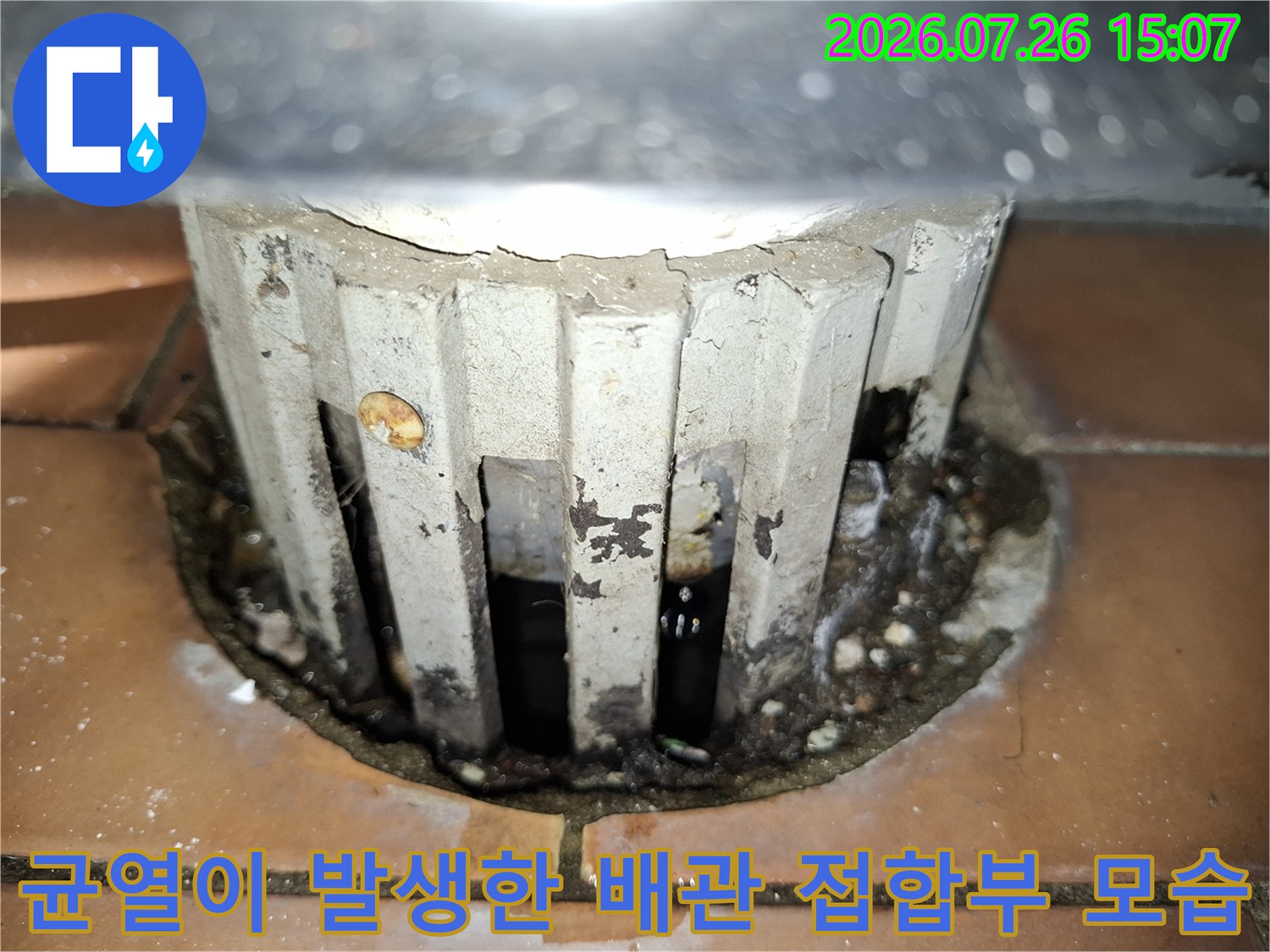 흰색 배관 덮개 주변으로 시멘트 마감재가 갈라지고 오염된 누수 지점 사진