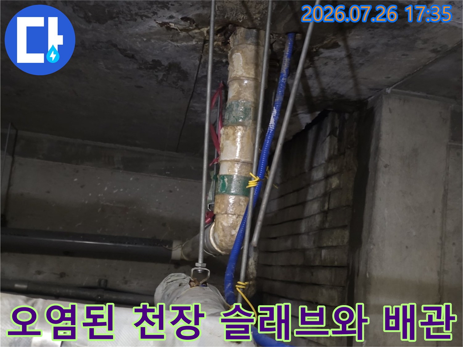물이 스며들어 변색된 콘크리트 천장에 설치된 여러 가닥의 배관들