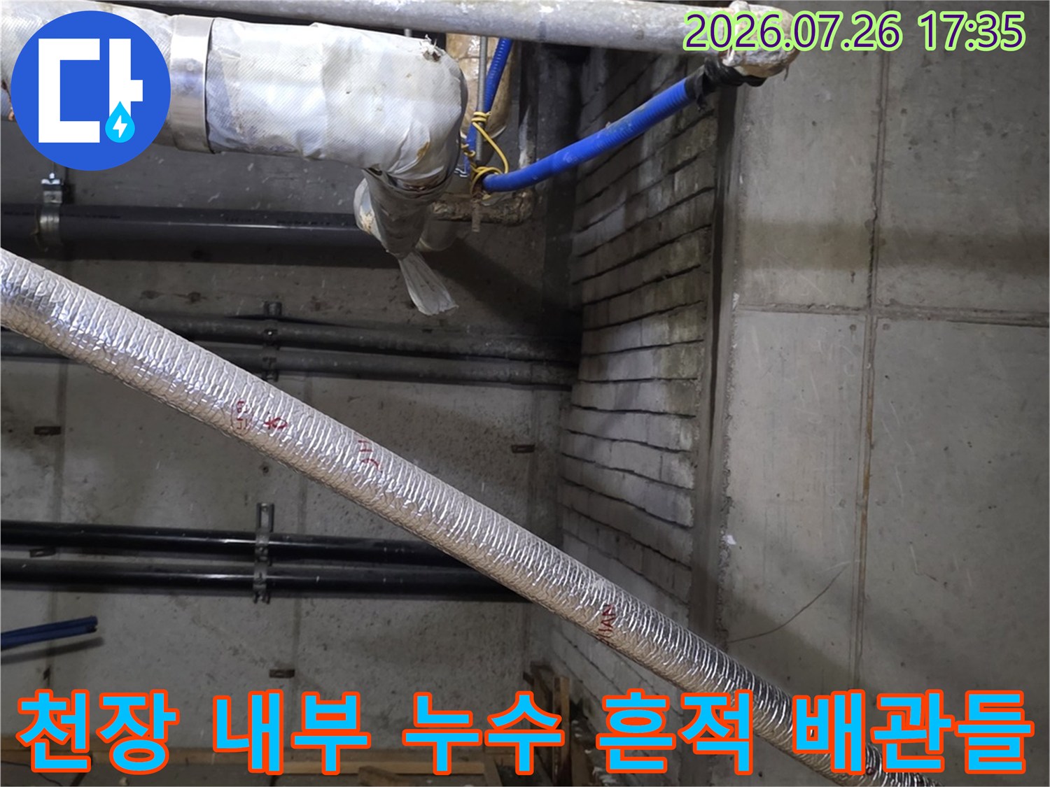은색 보온재와 파란색 배관이 설치된 상가 천장의 젖어 있는 콘크리트 면 사진