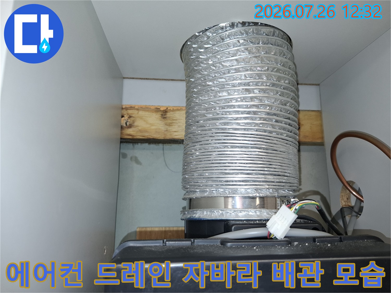 상단 천장 구조물에 고정된 은색의 주름진 에어컨 배관과 전기선-사진