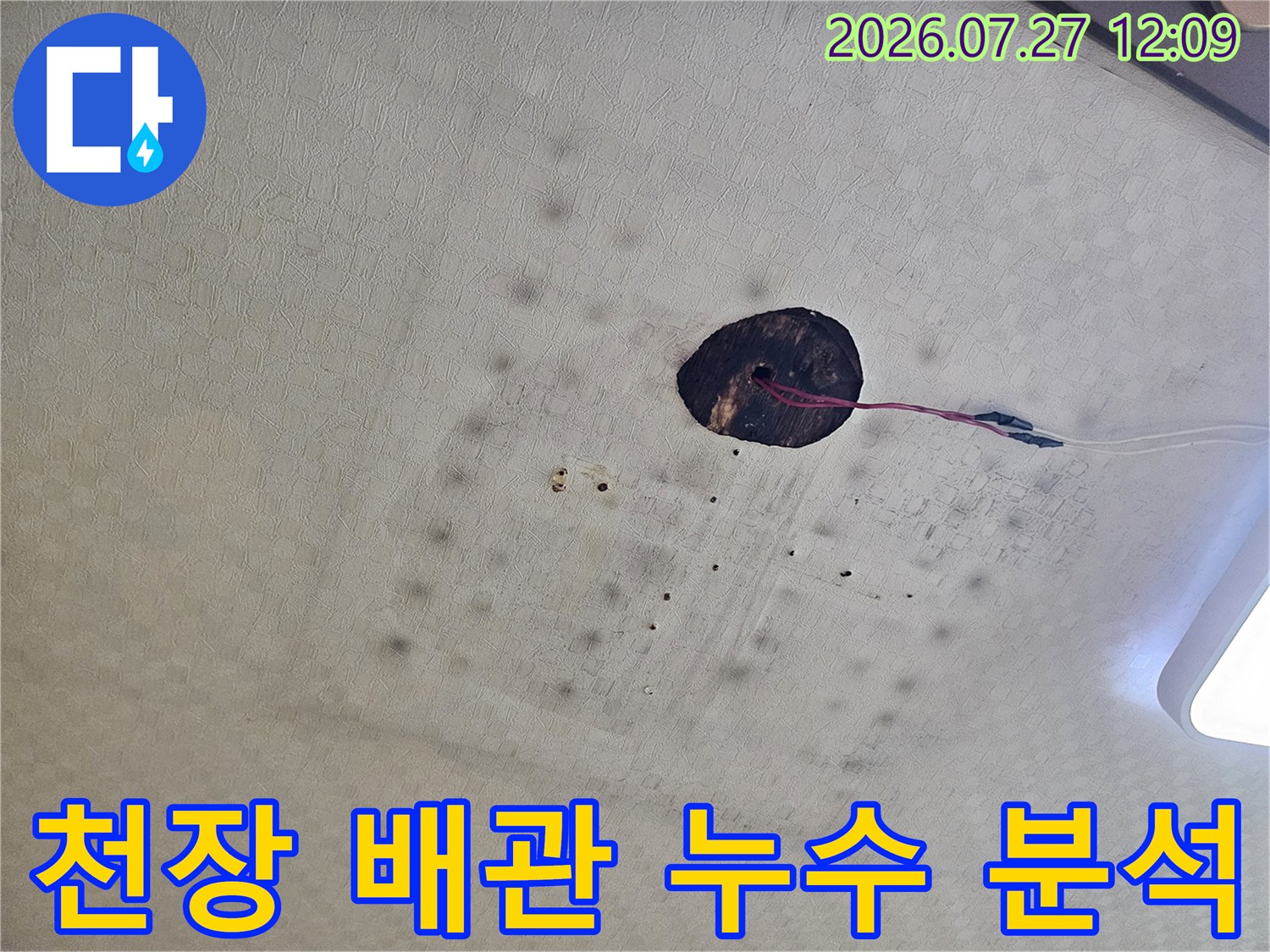 타공된 천장 안쪽으로 노출된 배관 연결부와 주변 환경을 점검하는 모습