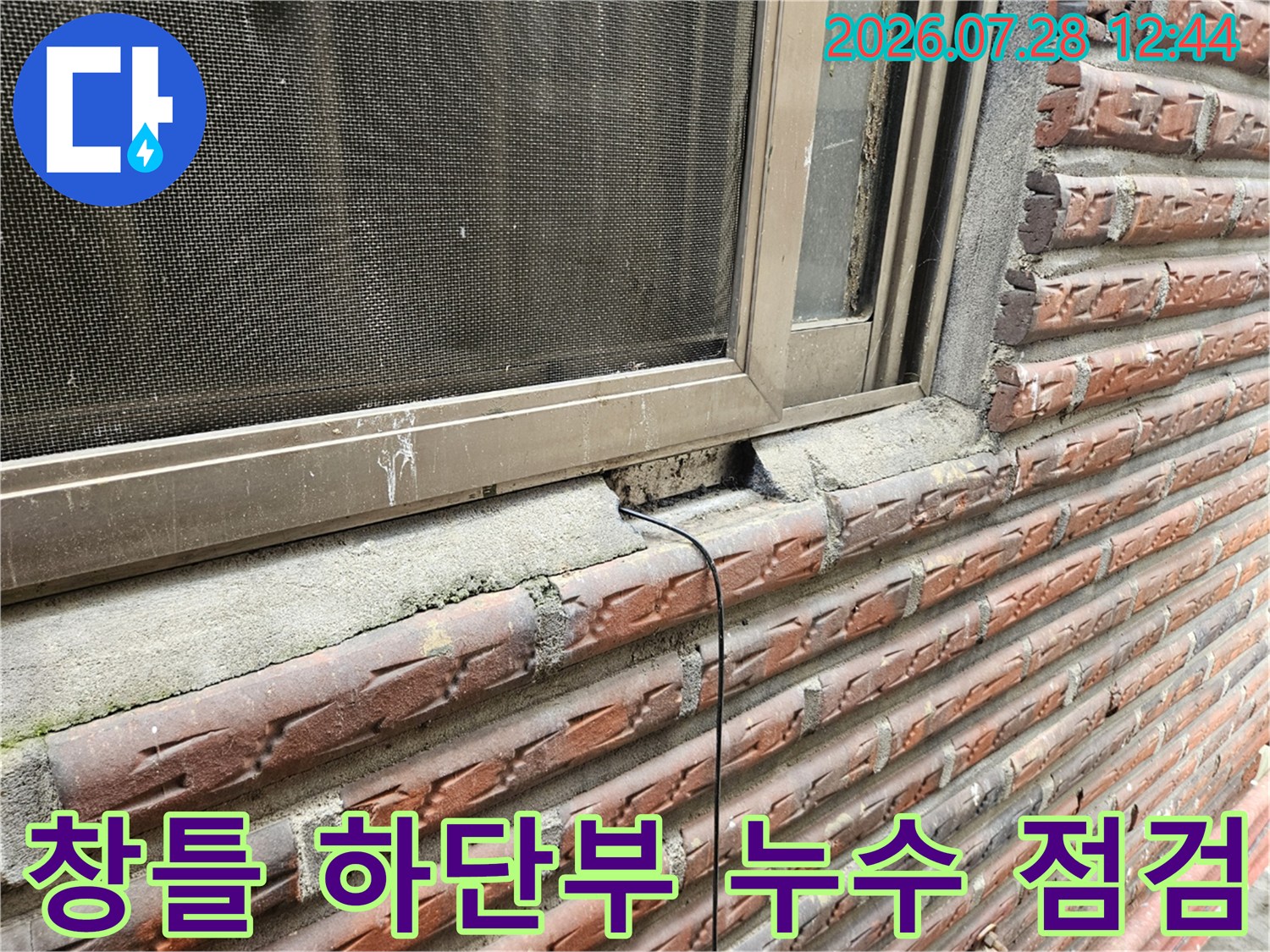 창틀 아래쪽의 노출된 배관과 파손된 외벽 틈새를 촬영한 사진