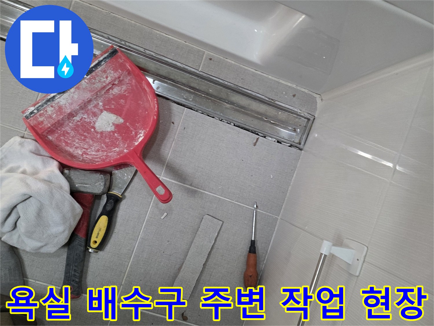 욕실 트랜치 배수구 주변의 타일과 작업 도구가 놓여 있는 모습입니다.