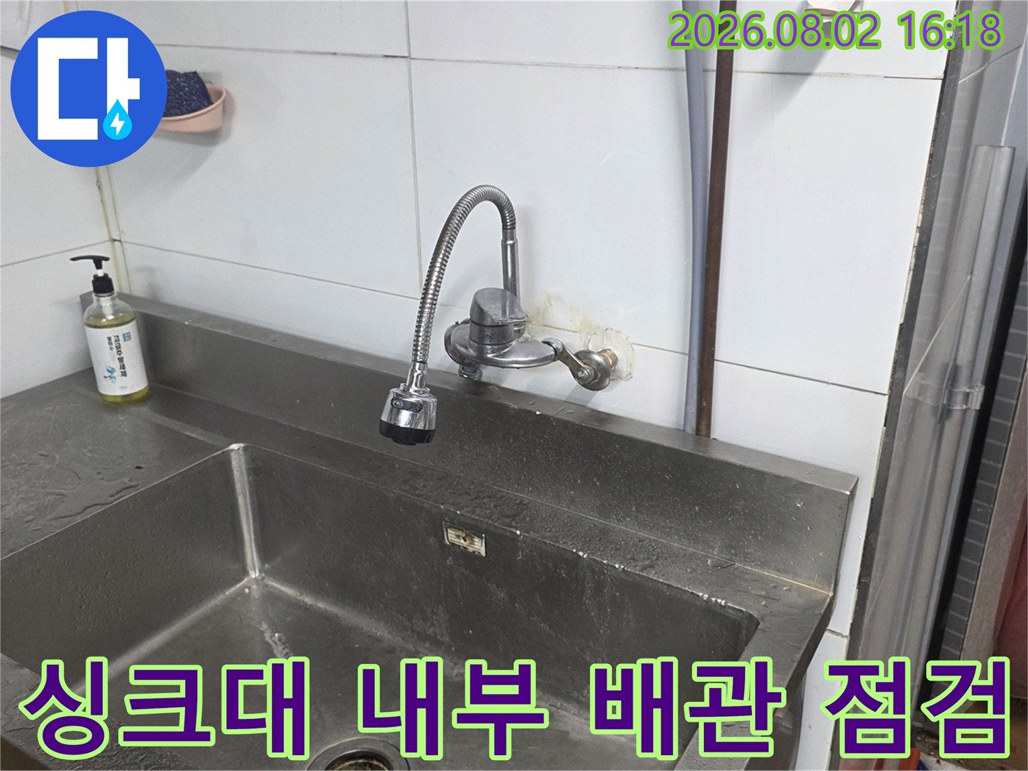 상업소 싱크대 내벽에 위치한 수도 배관의 상태를 상세히 살피는 장면