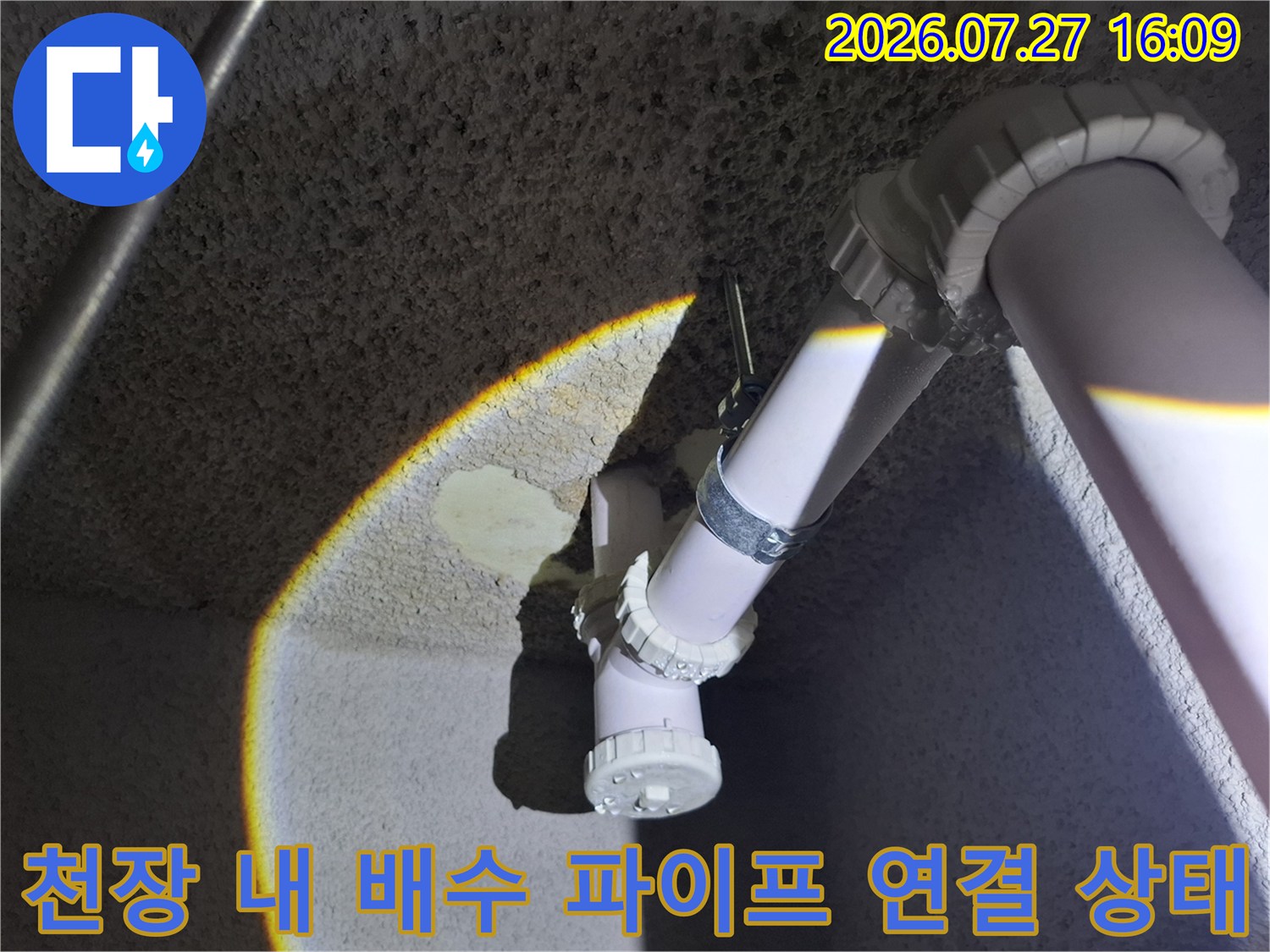 콘크리트 천장에 고정된 흰색 하수 배관-연결 캡 부위 상세 사진