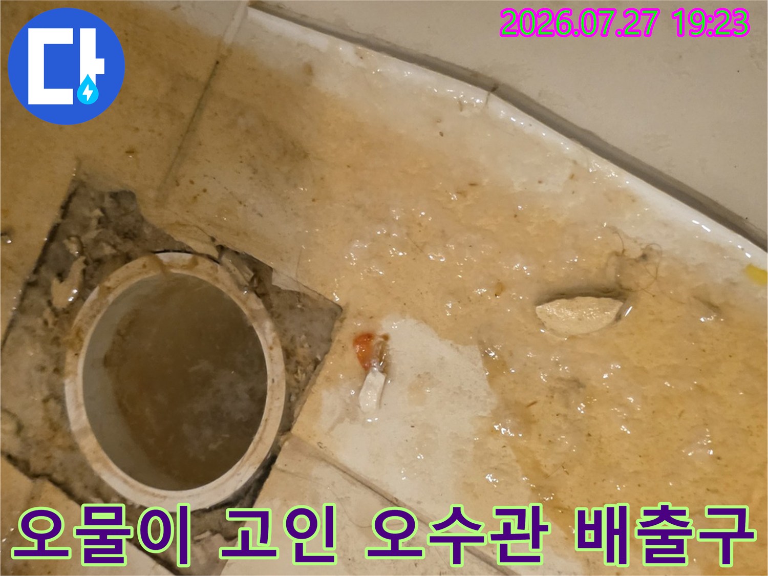 원형의 오수관 입구 주변으로 지저분한 물과 찌꺼기가 가득 차 있는 상태