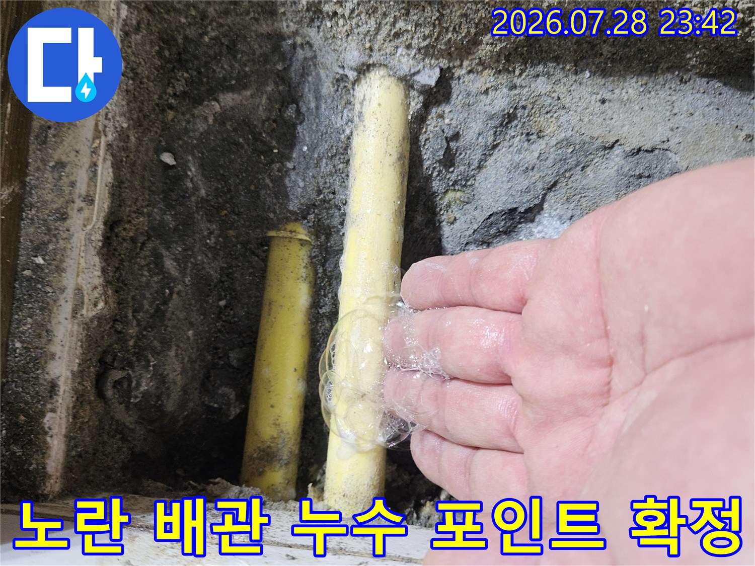 거품을 활용하여 노란색 배관의 손상된 연결 부위를 시각적으로 확인하는 기술적 단계