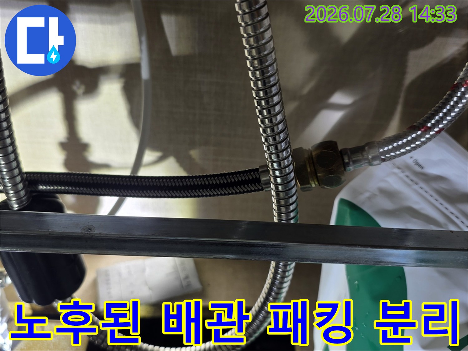 싱크대 하부 스테인리스 주름관의 연결 부위와 바닥에 놓인 검은색 고무 링 사진