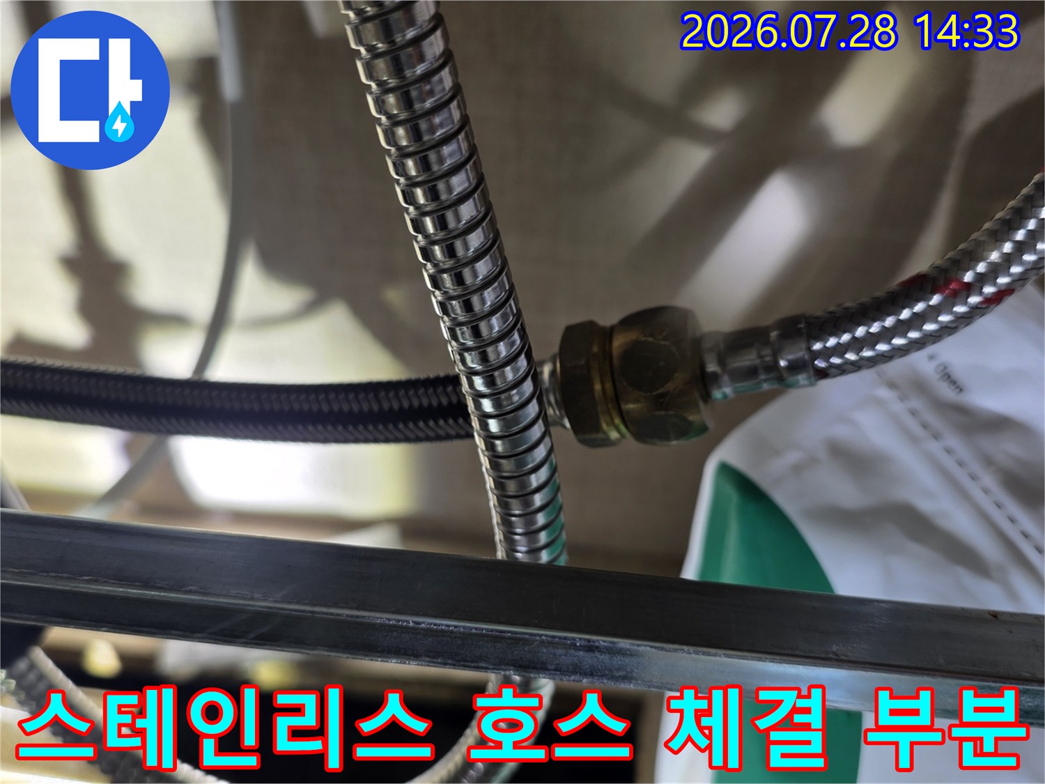 은색 스테인리스 주름 배관이 너트로 맞물려 있는-연결 지점의 근접 사진
