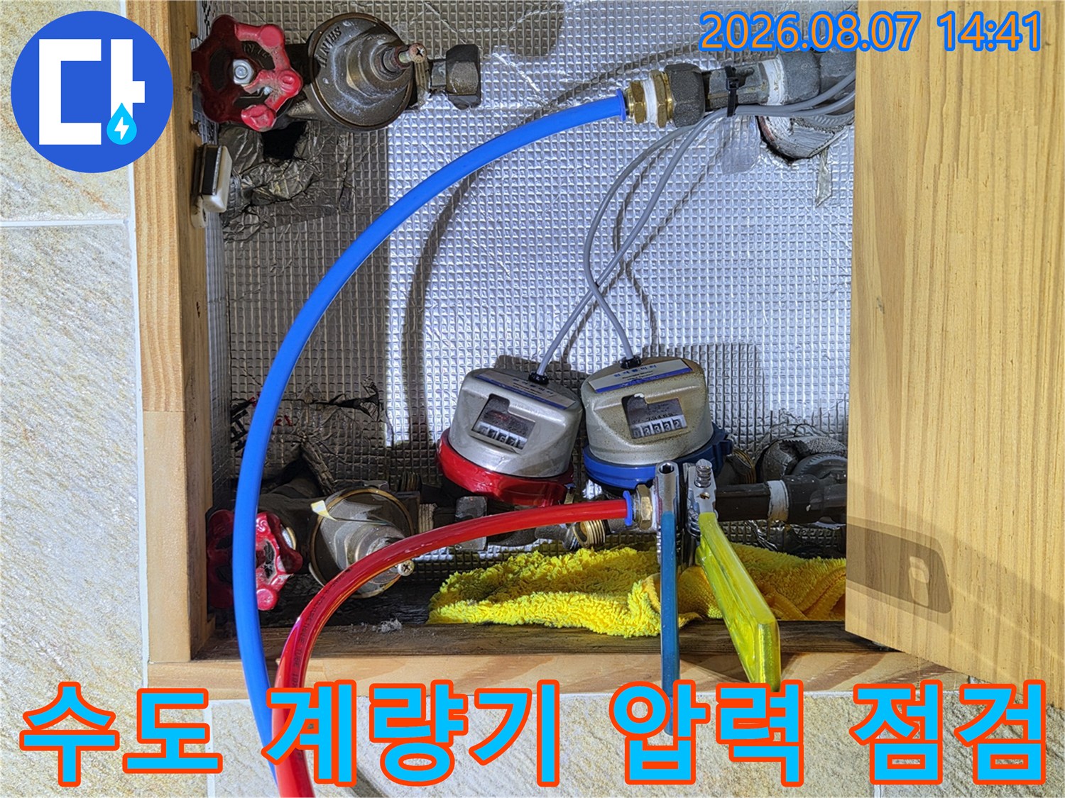 수도 계량기에 연결된 파란색과 빨간색 호스를 통한 배관 압력 테스트 장면