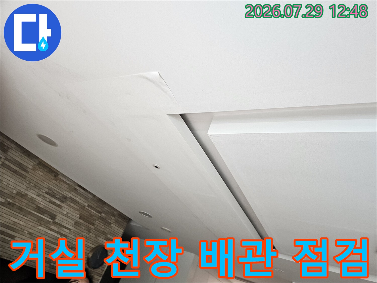거실 천장의 마감재를 뜯어내고 노출된 배관 부위를 점검하는 현장 모습