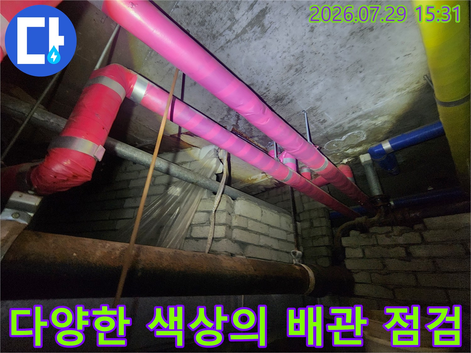 복잡하게 얽힌 천장 내부의 분홍색 및 파란색 배관과 연결부