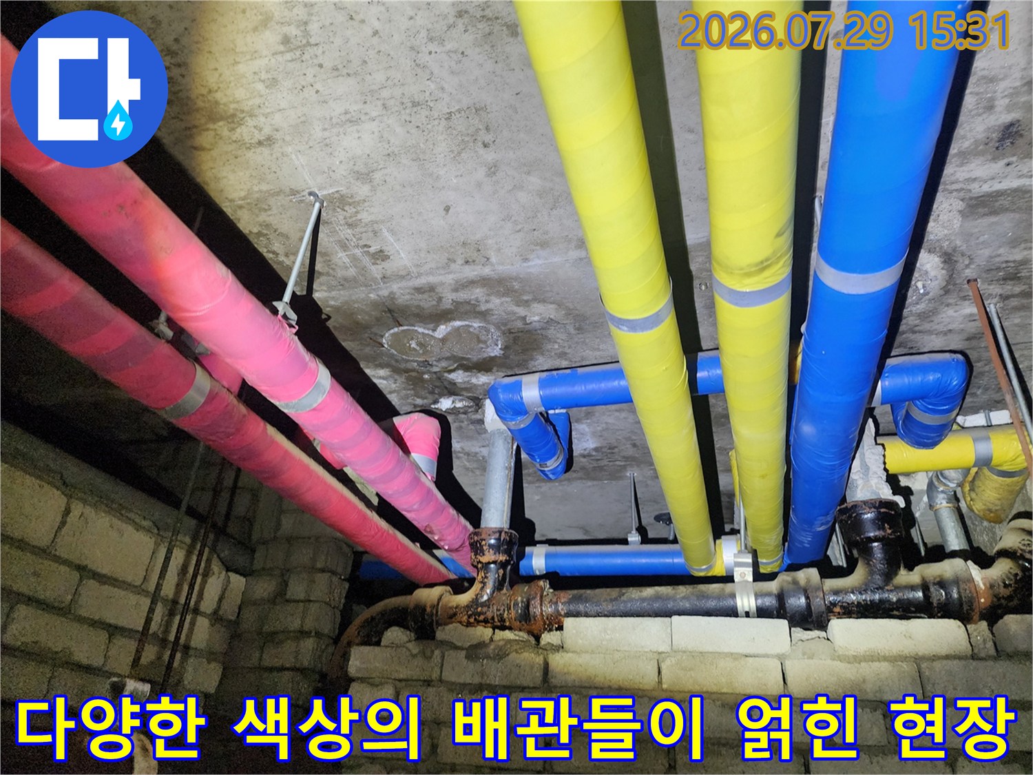 천장 내부에 노란색과 분홍색 그리고 파란색 보온재를 입힌 다수의 배관이 설치된 모습