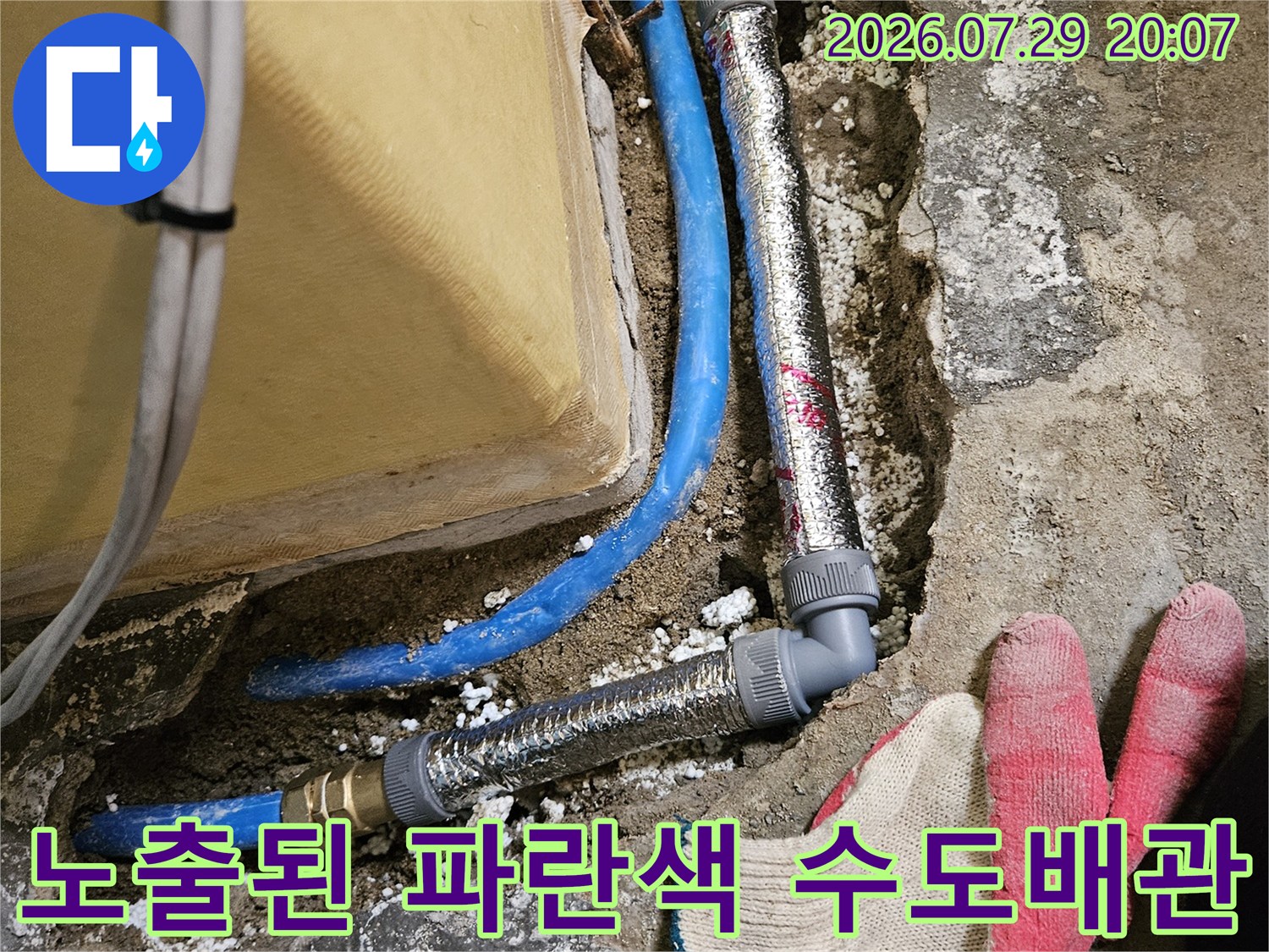 파란색 온수 배관과 은박 단열재로 보강된 연결 부위의 교체 공사 장면
