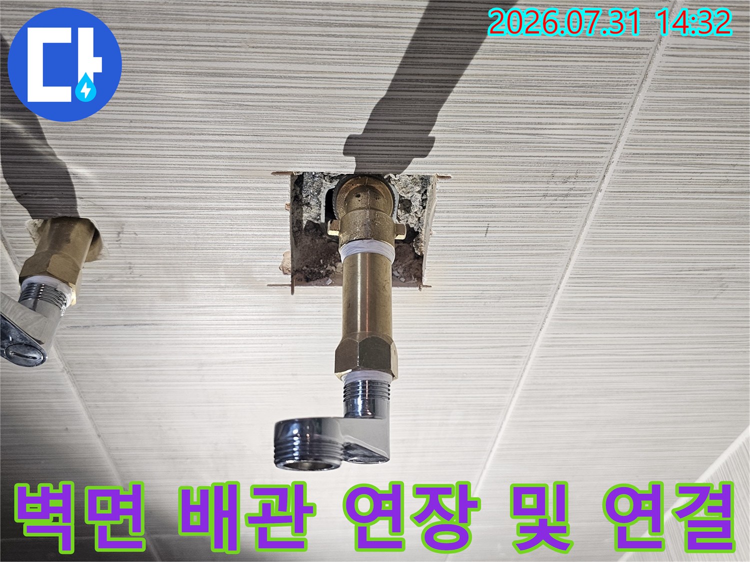 욕실 벽체에 고정된 금속 소재의 배관 연장 부위 상세 사진