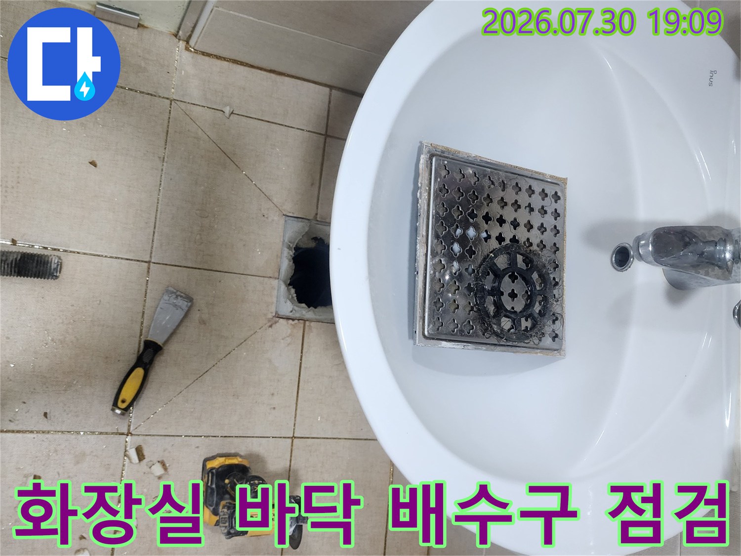화장실 세면대 아래쪽으로 노출된 배수구와 작업 도구가 있는 현장 모습