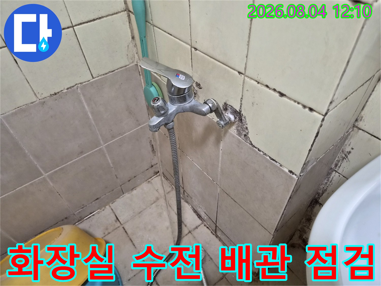타일 벽면에 설치된 수도 수전과 연결된 호스 및 노출 배관 점검 모습