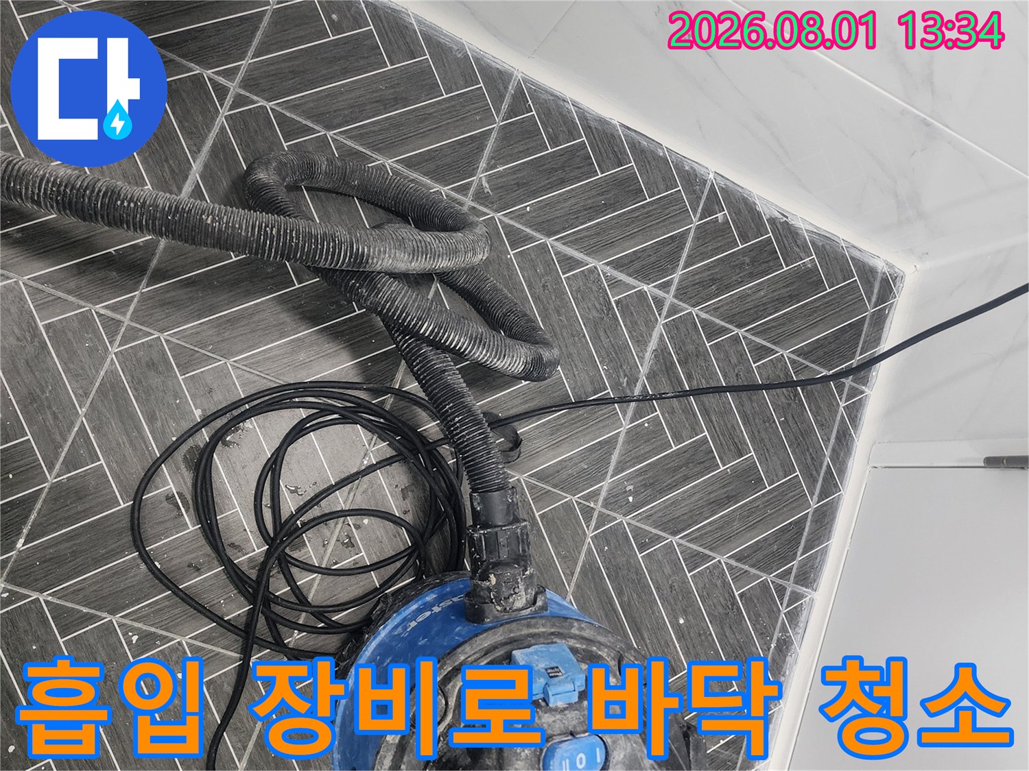 청소용 진공 흡입 기기를 사용하여 화장실 타일과 틈새 먼지를 제거하는 모습