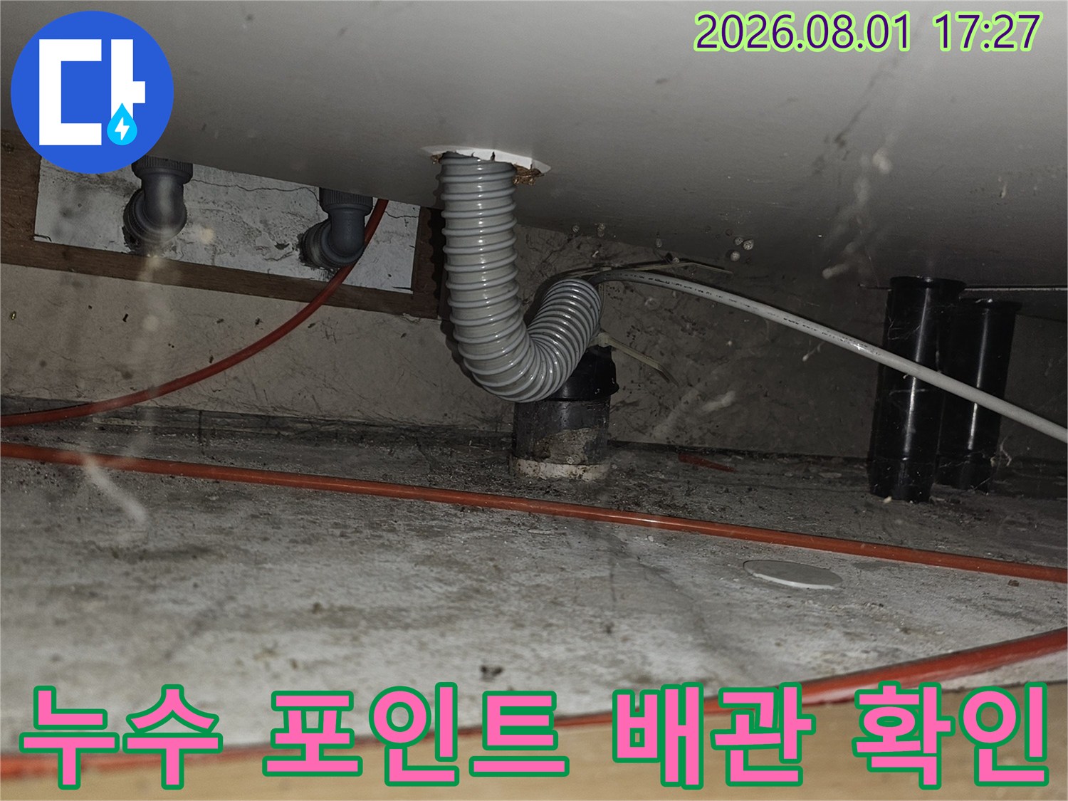 주방 하부 공간에 노출된 회색 굴곡형 배관과 연결부위 상세 점검