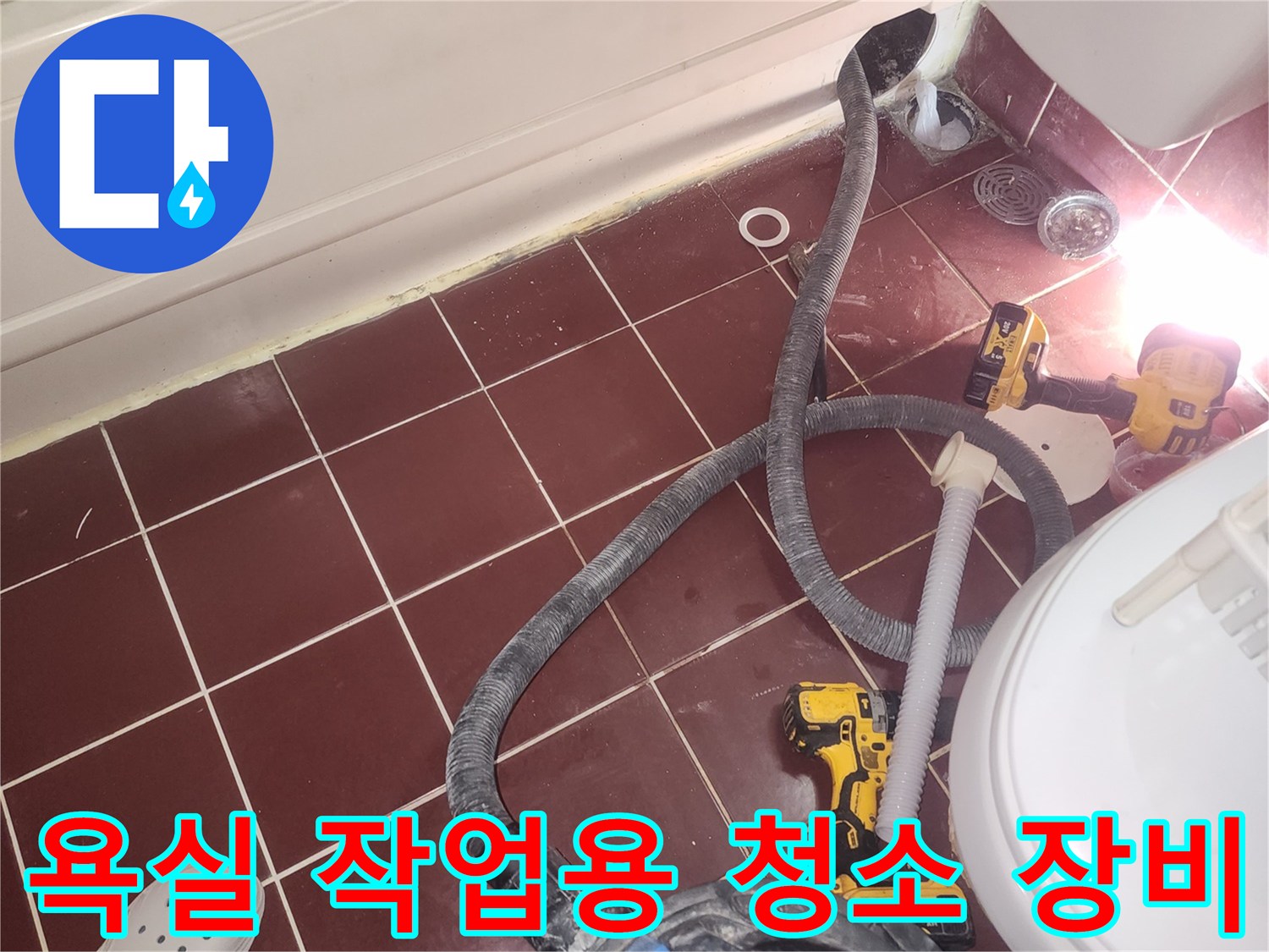 화장실 바닥 타일 위에서 작업 중인 진공 청소기와 전동 드릴 도구들