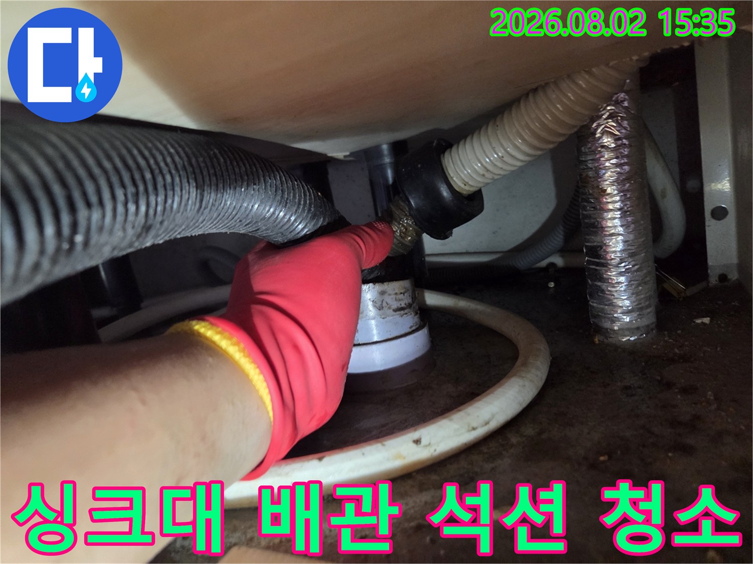 작업자가 싱크대 하단 배관에 석션 호스를 연결하여 내부 찌꺼기를 제거하는 모습