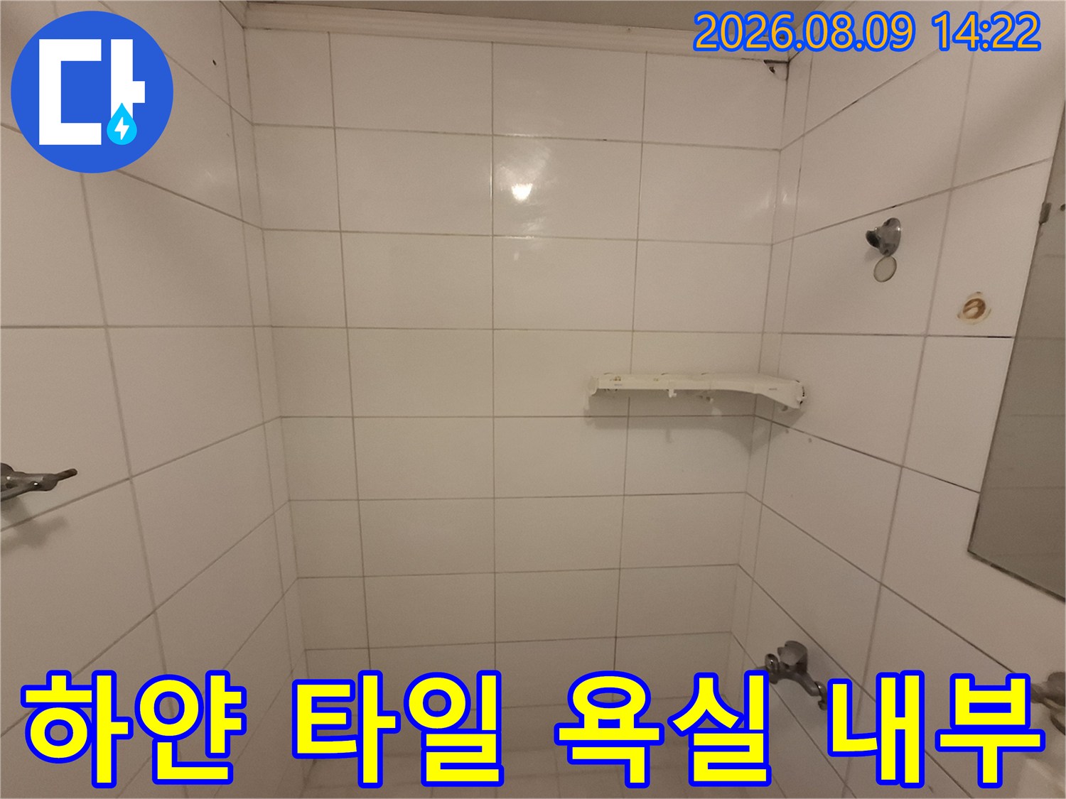 하얀색 타일로 마감된 화장실의 벽면과 바닥 모습입니다.
