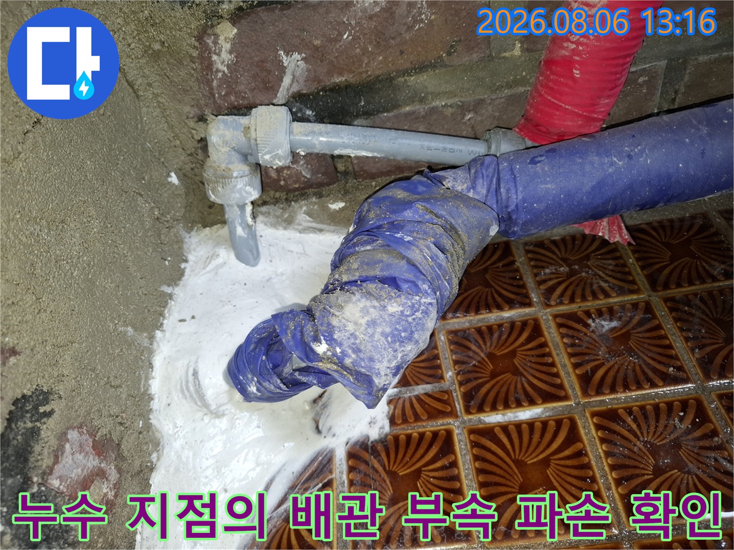 장갑을 끼고 물이 샌 배관 연결부의 거품과 누수를 점검하는 장면