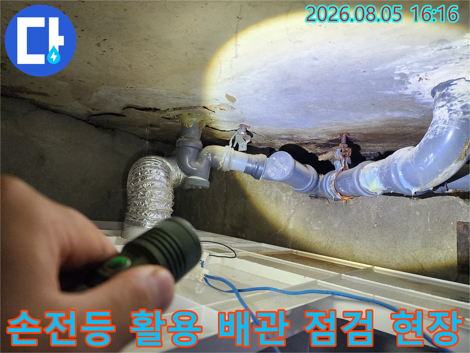 어두운 화장실 천장에서 손전등으로 배관 연결부 정밀 검사