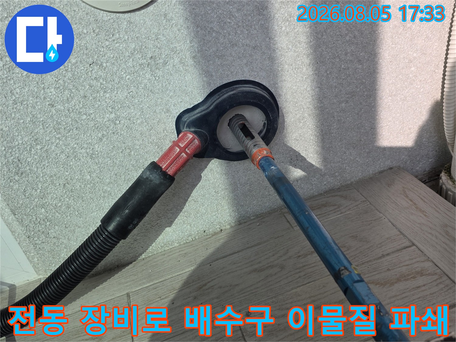회전식 배관 소통 장비를 사용하여 세탁실 배수 라인을 청소하는 장면